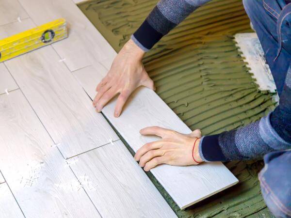 Vue en contre-plongée d'un artisan carreleur posant du carrelage à Strasbourg.